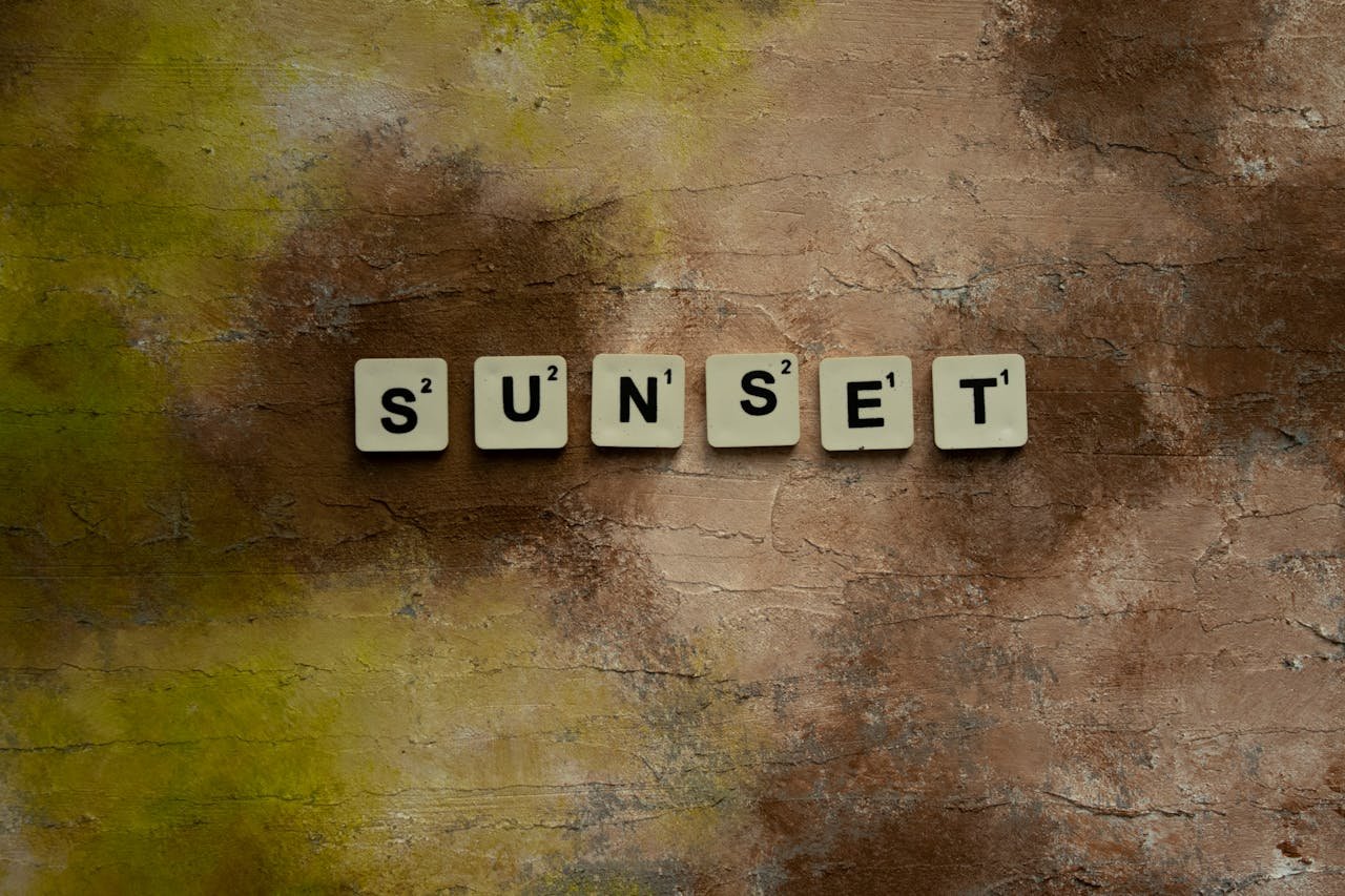 Creative composition with Scrabble tiles spelling 'sunset' on a textured surface.
