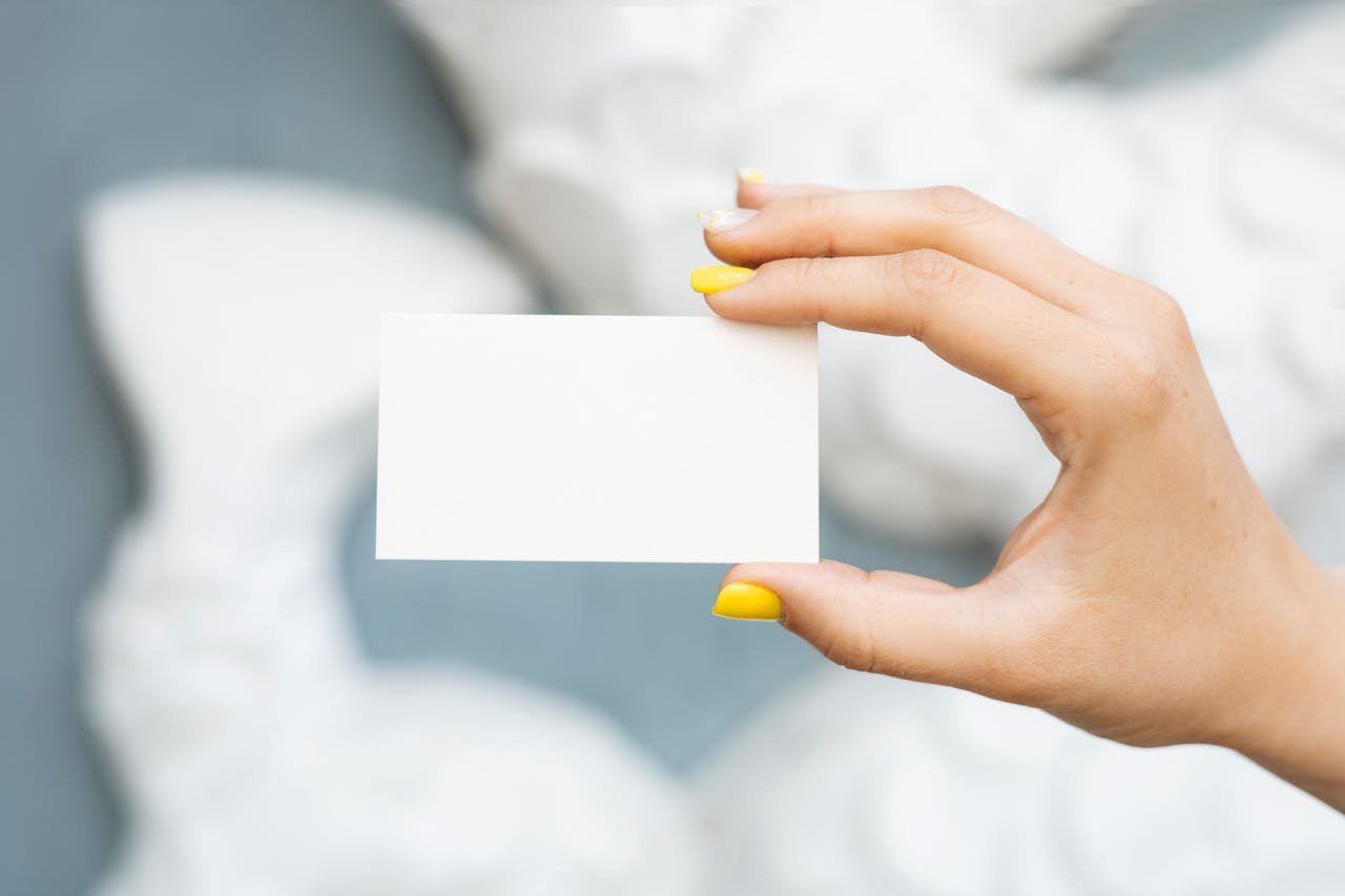 Minimalistic close-up of a hand displaying a blank business card with a blurred background, perfect for mockups.